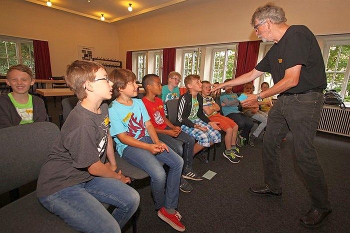 Larifari zeigt einer Gruppe von Kindern, wie ein Band aus einem Ring gelöst wird.